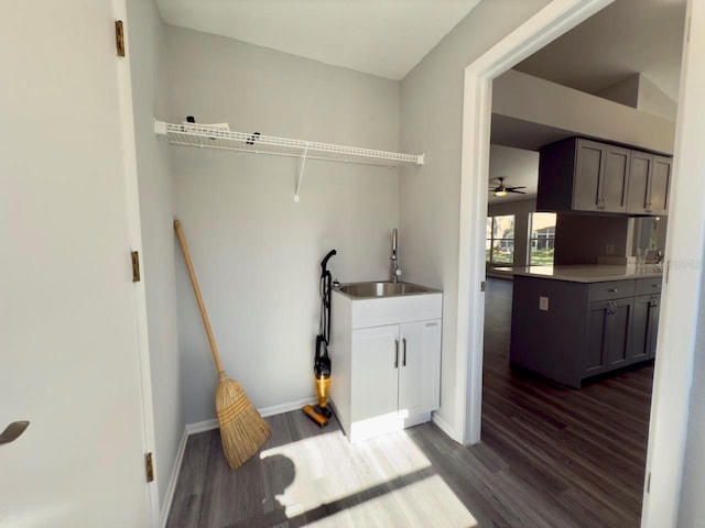 laundry area with dark wood-type flooring, ceiling fan, and sink