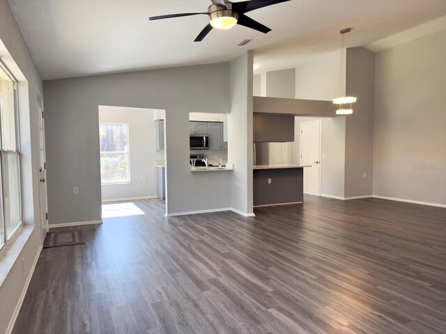 unfurnished living room featuring vaulted ceiling, dark hardwood / wood-style floors, and ceiling fan