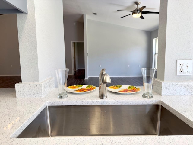 kitchen featuring light stone counters, sink, and ceiling fan