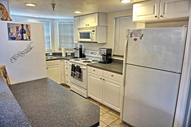 kitchen featuring light tile floors, white cabinets, sink, white appliances, and a textured ceiling