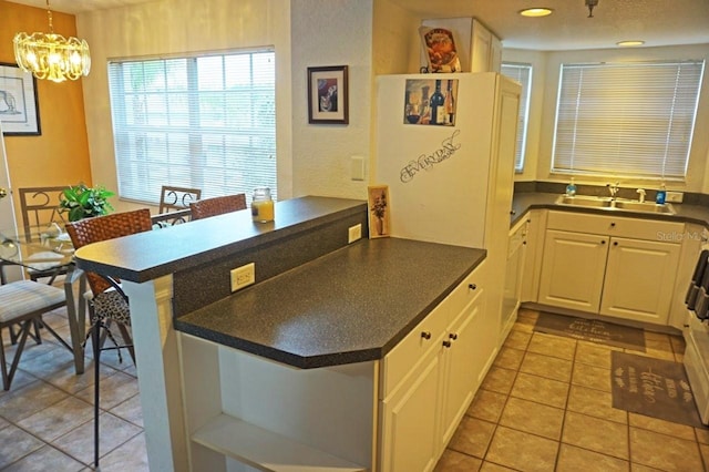 kitchen with pendant lighting, kitchen peninsula, white cabinetry, and light tile floors