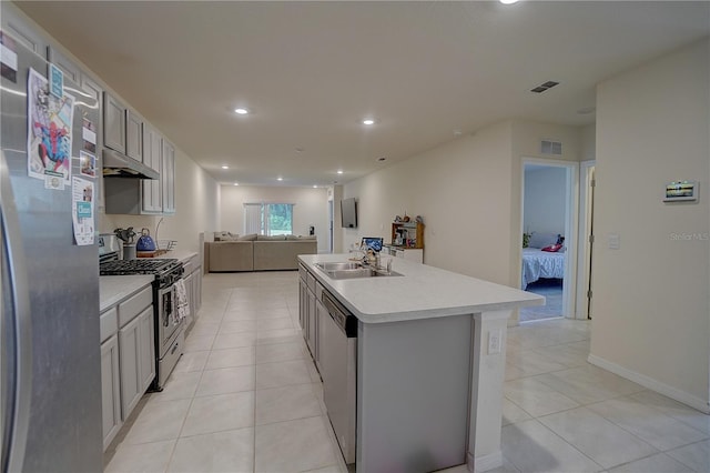 kitchen featuring stainless steel appliances, sink, an island with sink, and light tile floors