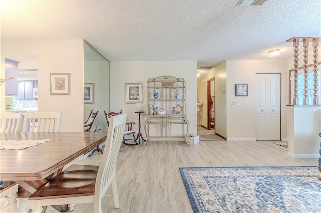 dining area featuring a textured ceiling and light hardwood / wood-style flooring