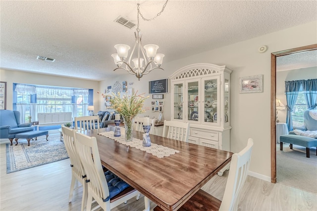 dining area featuring plenty of natural light, light hardwood / wood-style floors, and a textured ceiling