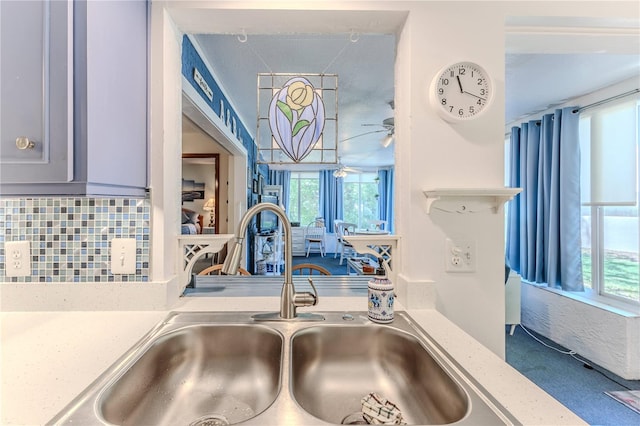 room details with decorative backsplash, light stone counters, ceiling fan, and sink