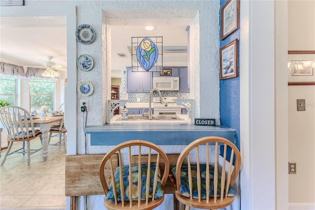 interior space with tile patterned floors, decorative backsplash, ceiling fan, and sink