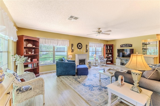 living room featuring a textured ceiling, light hardwood / wood-style flooring, and ceiling fan