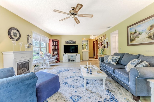 living room with a textured ceiling, light hardwood / wood-style flooring, and ceiling fan