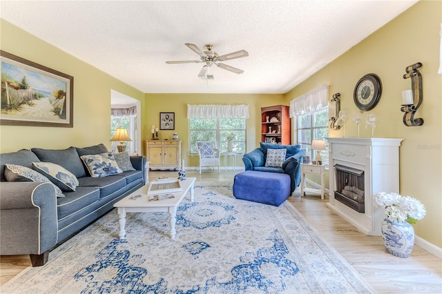 living room featuring ceiling fan, light hardwood / wood-style floors, and a textured ceiling