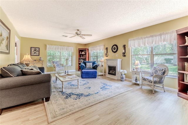 living room with ceiling fan, light hardwood / wood-style floors, and a textured ceiling