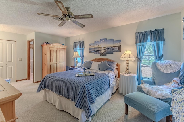 bedroom featuring a textured ceiling, light colored carpet, and ceiling fan