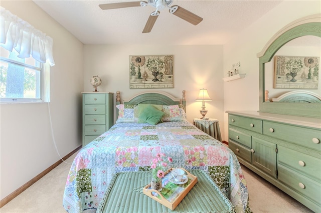 bedroom with ceiling fan, light colored carpet, and a textured ceiling