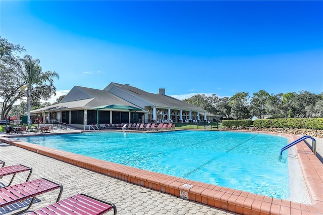 view of swimming pool featuring a sunroom and a patio