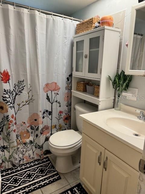 bathroom featuring tile floors, large vanity, and toilet