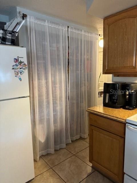 kitchen with white refrigerator, light tile floors, and range