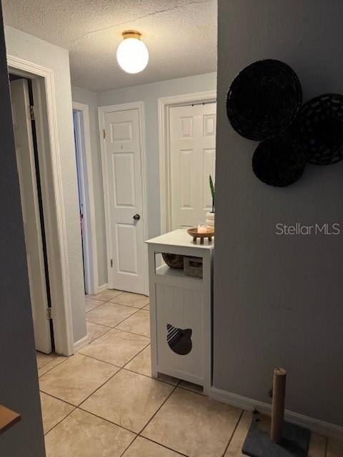 corridor with light tile flooring and a textured ceiling