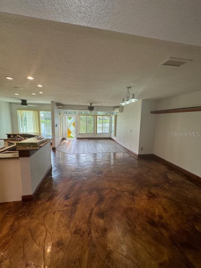 unfurnished living room featuring ceiling fan, a textured ceiling, and plenty of natural light