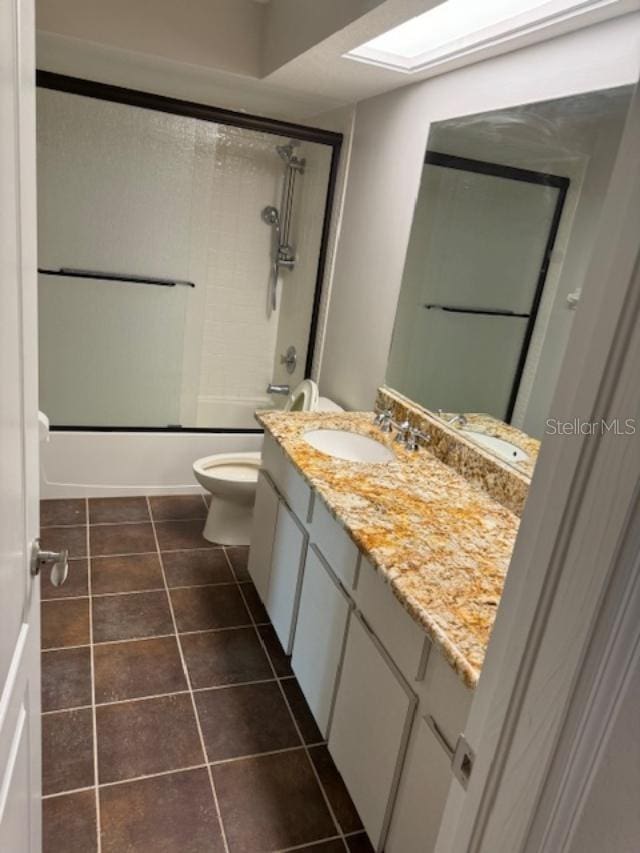 full bathroom with toilet, tile patterned flooring, vanity, enclosed tub / shower combo, and a skylight