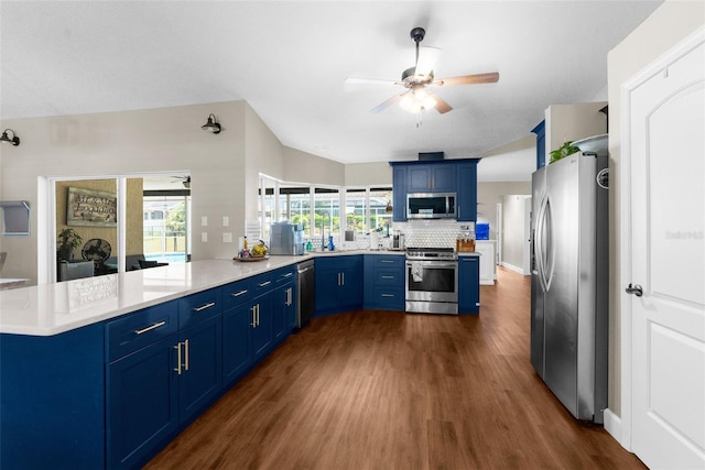 kitchen featuring kitchen peninsula, dark wood-type flooring, ceiling fan, blue cabinets, and appliances with stainless steel finishes