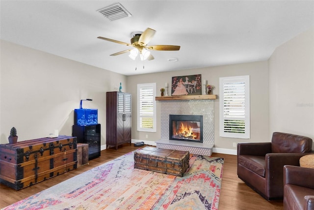 living room featuring a brick fireplace, hardwood / wood-style flooring, and ceiling fan