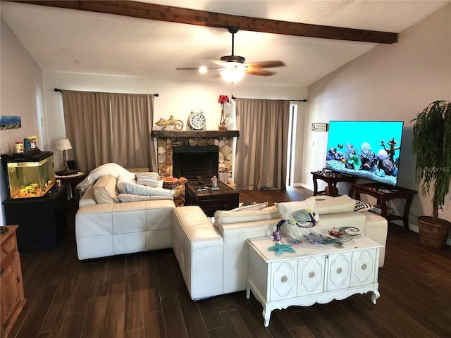 living room with ceiling fan, a stone fireplace, dark wood-type flooring, lofted ceiling with beams, and a textured ceiling