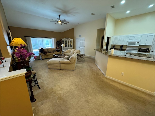 carpeted living room with high vaulted ceiling and ceiling fan