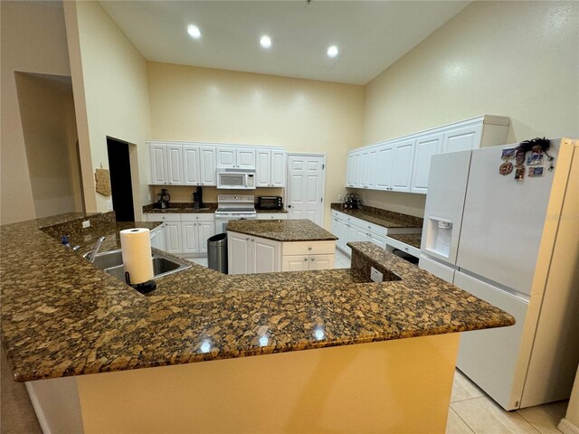 kitchen featuring a large island, white cabinetry, white appliances, and a towering ceiling