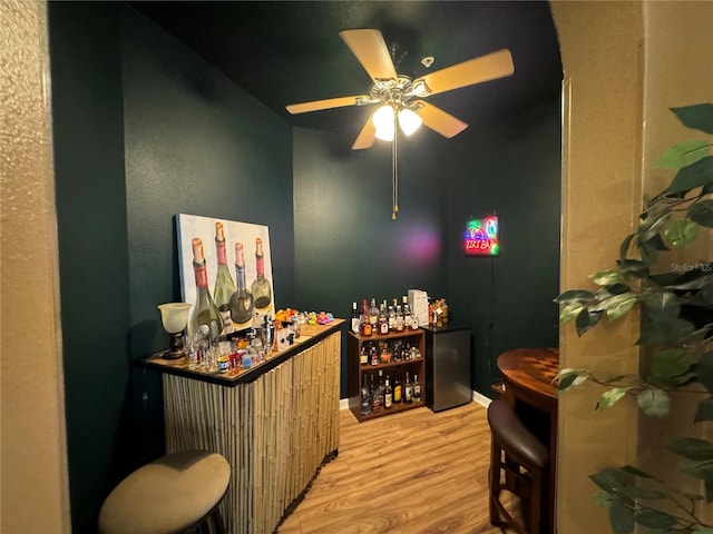 bar with ceiling fan and wood-type flooring