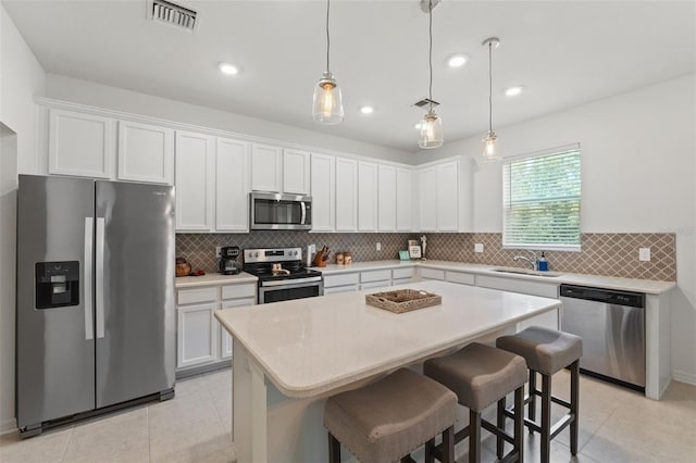 kitchen featuring tasteful backsplash, light tile flooring, a center island, sink, and appliances with stainless steel finishes