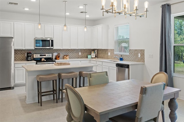 kitchen with appliances with stainless steel finishes, a healthy amount of sunlight, and decorative light fixtures