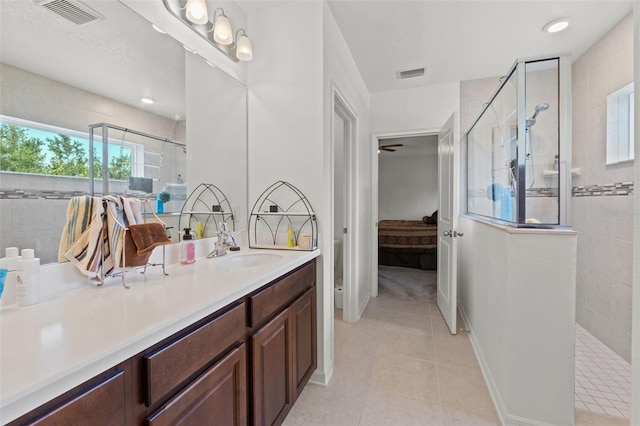 bathroom with tile floors, vanity with extensive cabinet space, and an enclosed shower