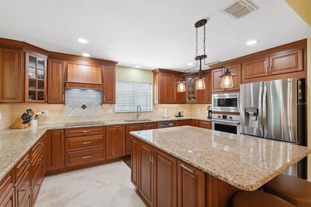 kitchen featuring sink, stainless steel appliances, premium range hood, decorative light fixtures, and a breakfast bar