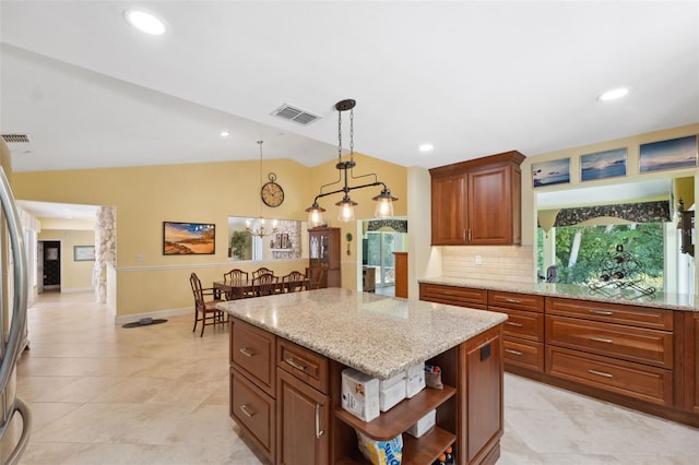 kitchen with tasteful backsplash, light stone counters, pendant lighting, vaulted ceiling, and a kitchen island