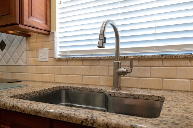 room details with sink, light stone countertops, and backsplash