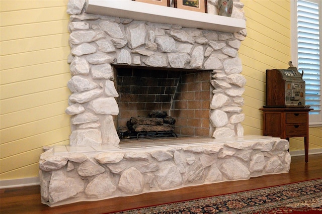 interior details featuring a stone fireplace, wood walls, and hardwood / wood-style flooring