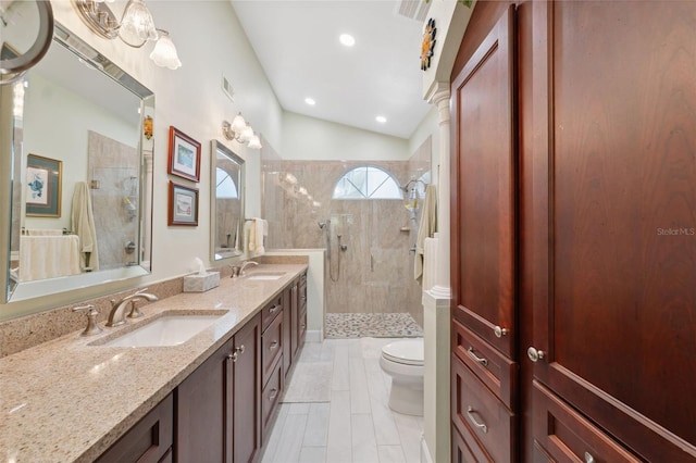 bathroom featuring toilet, vanity, tiled shower, and vaulted ceiling