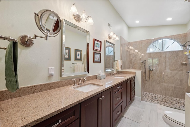 bathroom with a tile shower, vanity, toilet, and lofted ceiling