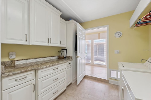 laundry room featuring cabinets, light tile patterned floors, and washer and dryer