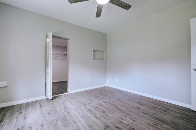 unfurnished bedroom featuring ceiling fan, a spacious closet, hardwood / wood-style flooring, and a closet