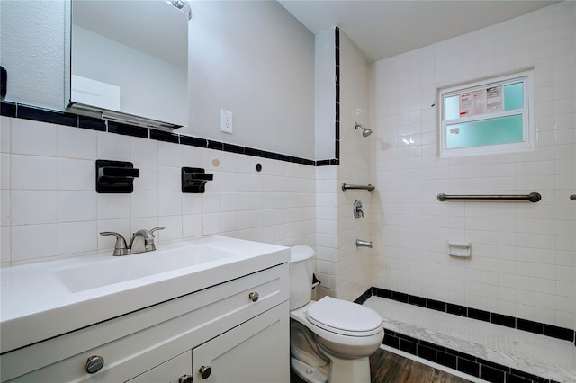 full bathroom with tile walls, toilet, vanity, and tiled shower