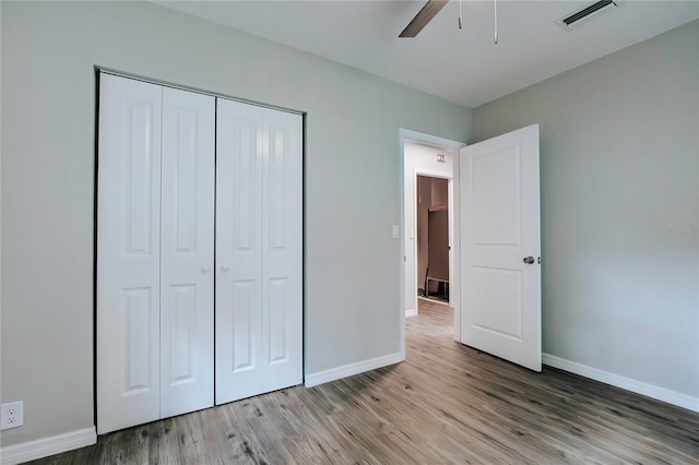 unfurnished bedroom featuring ceiling fan, light hardwood / wood-style floors, and a closet