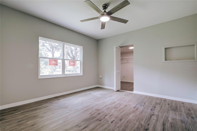 unfurnished bedroom featuring baseboards, wood finished floors, a closet, and ceiling fan