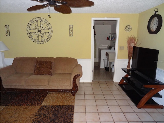 living room featuring tile patterned flooring, ceiling fan, washing machine and dryer, and a textured ceiling