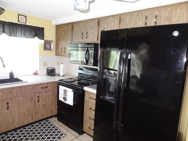 kitchen with black appliances, light tile patterned floors, sink, and a textured ceiling