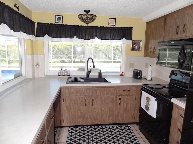 kitchen featuring a textured ceiling, sink, a healthy amount of sunlight, and black appliances