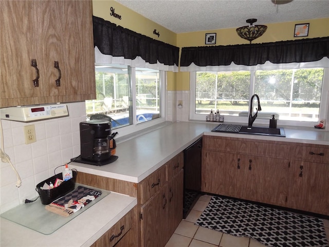 kitchen with a textured ceiling, black dishwasher, light tile patterned floors, and sink