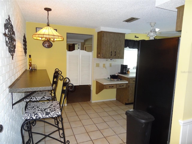 kitchen featuring pendant lighting, ceiling fan, light tile patterned flooring, and a textured ceiling