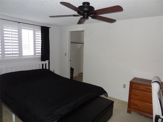 bedroom featuring a walk in closet, ceiling fan, a closet, and a textured ceiling