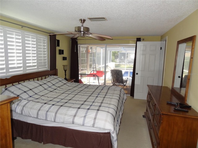 bedroom with ceiling fan, light colored carpet, and a textured ceiling