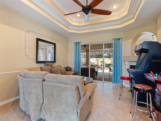 living room with ceiling fan, a raised ceiling, ornamental molding, and light tile patterned floors